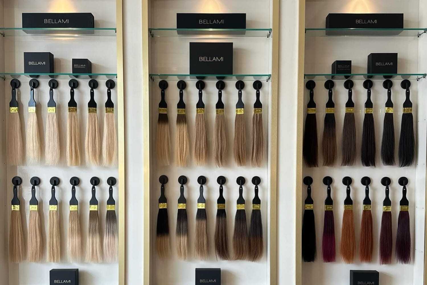 Display of assorted Bellami hair extensions in various shades on a wall.
